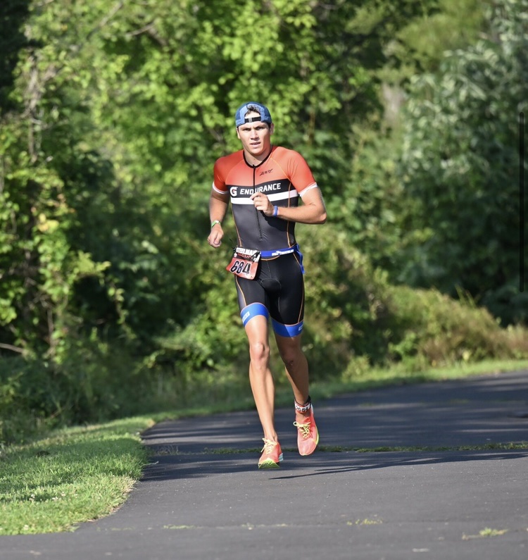 Triathlete running on a tree-lined road